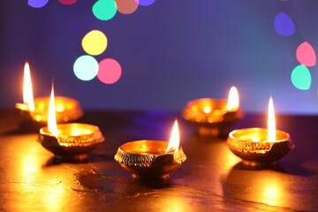 Diwali celebration. Diya lamps on dark table against blurred lights