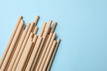 Bamboo drinking straws on light blue background, top view. Space for text