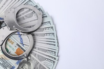 Corruption concept. Handcuffs and dollar banknotes on white background, top view. Space for text