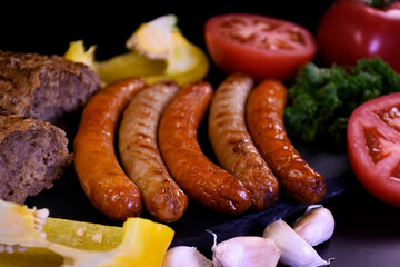 Grilled sausages with fresh vegetables and bread.  Picnic food.