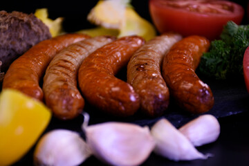 Grilled sausages with fresh vegetables and bread.  Picnic food.