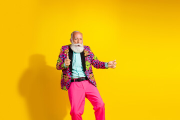Photo portrait of attractive retired man have fun dance dressed stylish colorful pink fancy clothes isolated on yellow color background