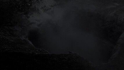 A hole in the ground from which ominous smoke or fog rises. Awesome black and white video for Halloween