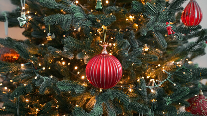 Christmas red ornament close-up Christmas tree flickering light hanging on beautifully lit. Festive...