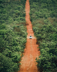 carro em estrada de terra com vegetação verde ao lado 