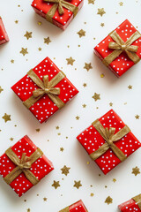Fototapeta premium Vibrant red gift boxes, adorned with golden ribbons, sit on a pristine white background. Shining gold stars are sprinkled around the boxes, creating a beautiful and festive composition, perfect for