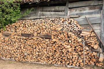 Firewood stacked in front of old wooden house in the countryside