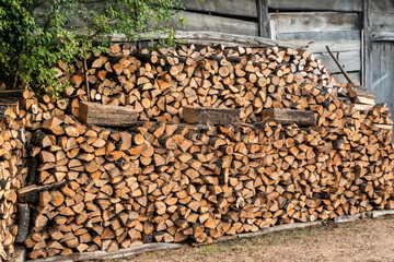 Firewood stacked in front of old wooden house in the countryside