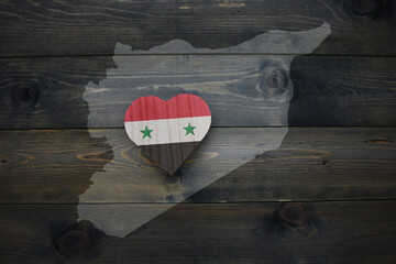 wooden heart with national flag of syria near map on the wooden background.