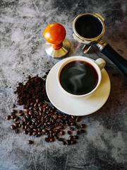 Coffee cup and beans with ground coffee on  gray background, Black coffee cup aromatic and making equipment, Tamper, Filter Basket