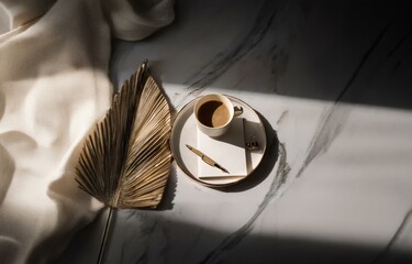A cup of coffee, pen, and blank paper on a tray, with a dried palm leaf and white fabric in the background.