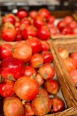 There are many red juicy pomegranates in wicker brown baskets in the supermarket. food sale. juicy fruits. copy space