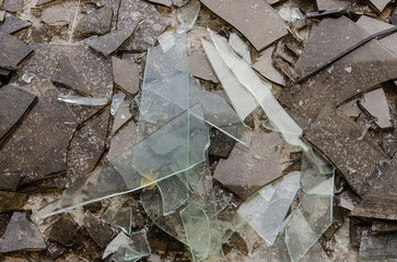 A close up view of a broken glass window with shards scattered around