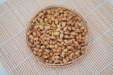 soybeans in a basket on a bamboo mat background.