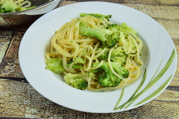 Eating hot spaghetti with broccoli and parmesan cheese in a plate