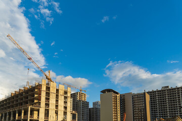 Construction cranes working on a new apartment building on a sunny day. Image evokes concepts such...