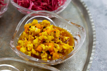 pickles made with chopped up carrots, cauliflower and other vegetables  in a crystal bowl .