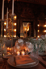 Modern luxury destination wedding decor in dark gold mode in historical Italian villa Arvedi with candelabras, gold chairs flowers and artworks
