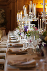 Modern luxury destination wedding decor in dark gold mode in historical Italian villa Arvedi with candelabras, gold chairs flowers and artworks