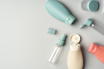 Collection of various reusable cosmetic containers arranged on a light gray background