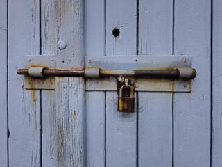 Old wooden door locked with rusty padlock