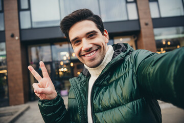 Photo of cheerful nice blogger man dressed trendy clothes recording video v-sign weekend day...