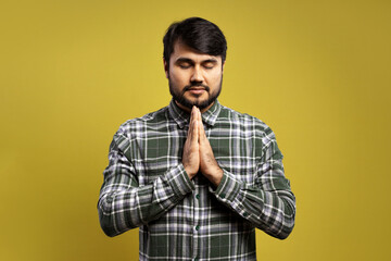 man with hands together at chest height and eyes closed