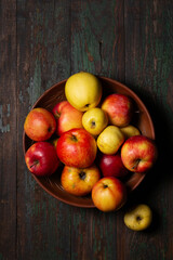 Juicy ripe apples in a large clay bowl on a wooden background