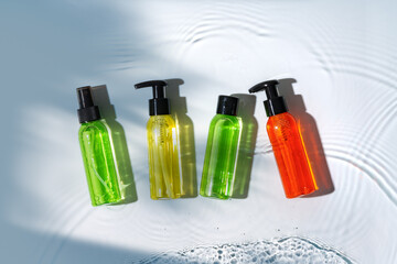 Colorful liquid soaps arranged on a smooth surface with ripples in warm sunlight