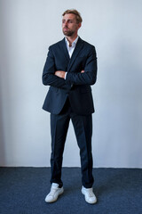 Portrait of the man in suite looking for at the camera. Serious portrait at white background. Young man with style hair and beard