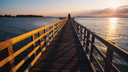 The planked passage to the lighthouse on the seashore during the golden hour at dawn