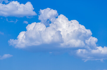 Bodies of cumulus white clouds rising against clear blue sky. Carefree summer background. Relaxation.