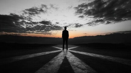 Fototapeta premium Silhouette of Man at Crossroads with Mountain Range in the Background
