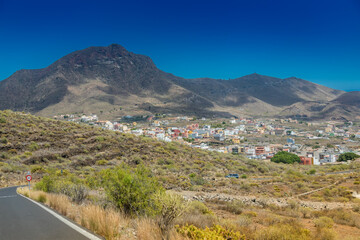 A panoramic view of San Miguel, Tenerife, nestled in a valley with rugged mountains rising in the background beneath a clear blue sky