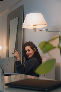 Young woman with creative ideas looks at the camera and points up with her finger, vertical image