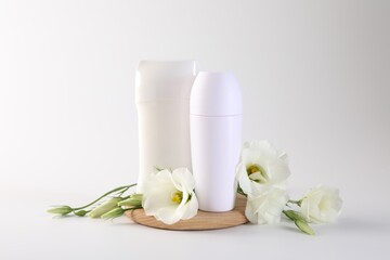 Different deodorants and beautiful eustoma flowers on white background
