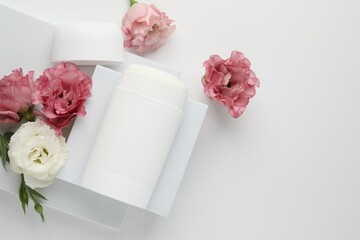 Solid deodorant and beautiful eustoma flowers on white background, top view