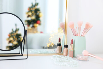 Makeup brushes, cosmetics and mirror on white table indoors