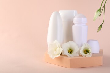 Different deodorants and beautiful eustoma flowers on beige background, space for text