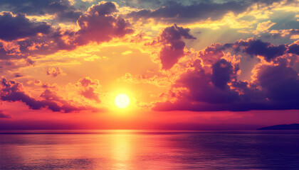 Fototapeta premium A vibrant sunset over the ocean with a dramatic sky of orange, purple and pink clouds.