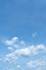 Beautiful fluffy white clouds drift across a clear blue sky