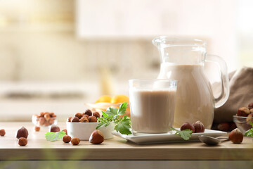 Hazelnut drink in glass and jug on wooden kitchen bench