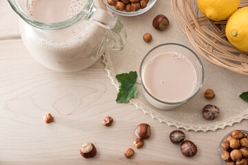 Hazelnut drink in glass and  jug on wooden kitchen bench