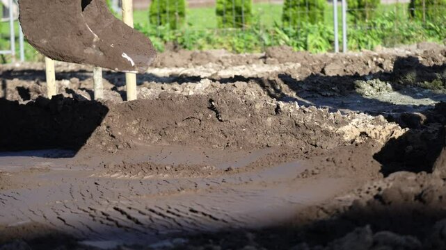 Mini excavator bucket working on earth moving in a construction project also paying the surface of the gravel, sand and mud