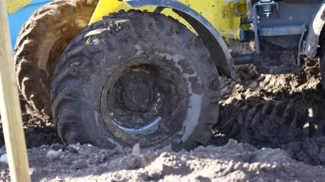 Construction loader equipment tires moving through rough mud terrain in construction yard in process