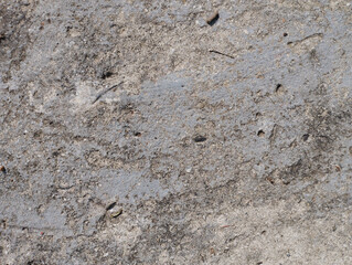Close-up textured image of rough, cracked concrete surface with visible grainy details, ideal for backgrounds or construction themes