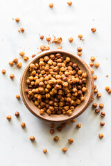 Above view of a bowl of spicy roasted chick peas with them scattered around.