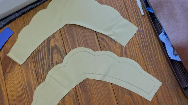 Women's hands cut out a piece of an ethnic Slavic crown on a wooden table with scissors from an adhesive woven interlining fabric. Seamstress and her workplace. Eco-leather headdress.