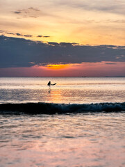 Fototapeta premium A surfer waits for waves at sunset, Andaman Sea/KohPayam, Thailand, Southeast Asia