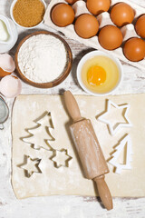 Ingredients for baking Christmas cookies on table. Dough, cookie cutters and rolling pin, vertical